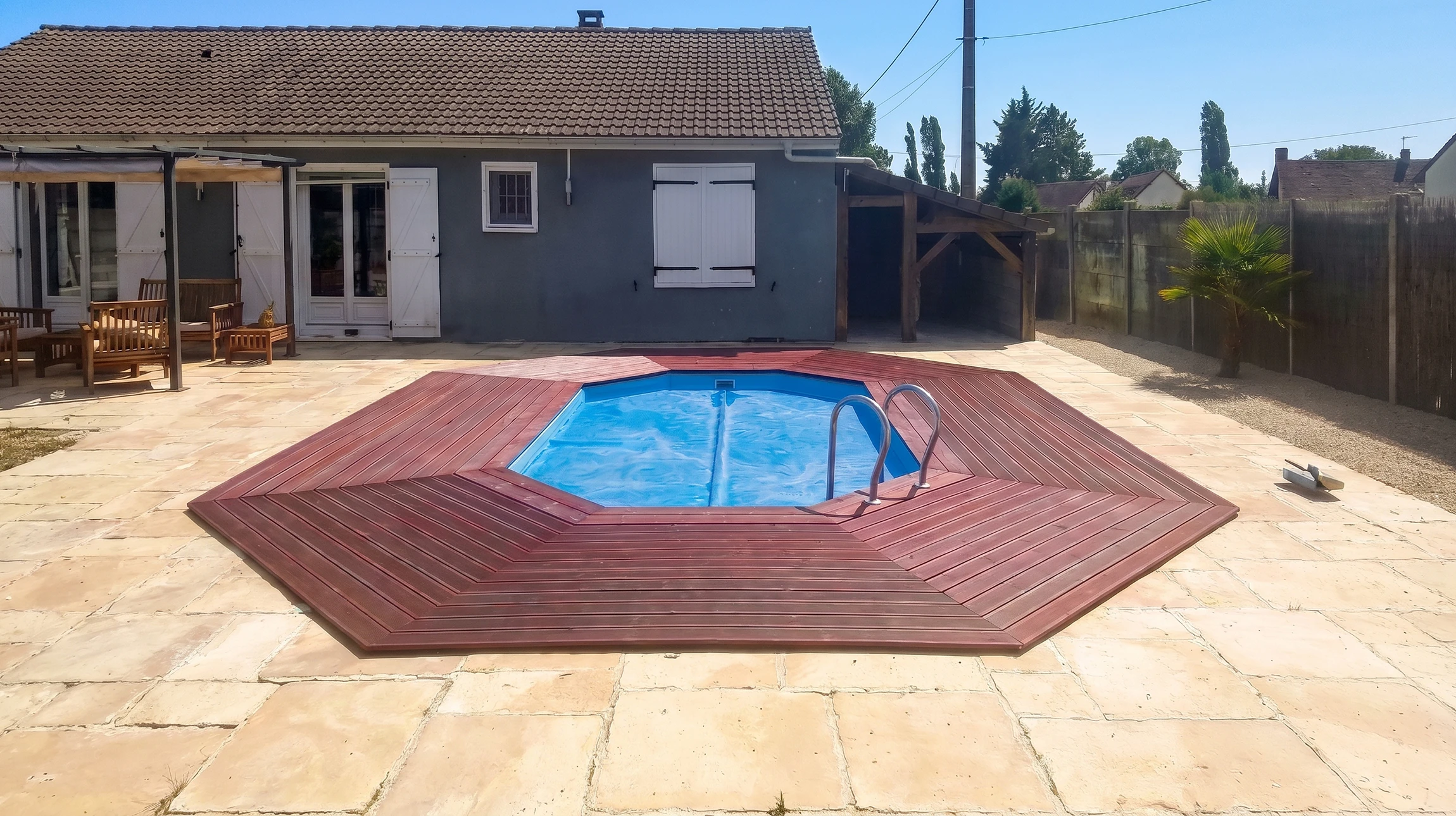 Piscine rectangulaire extérieure avec margelles en béton gris et plage en bois composite